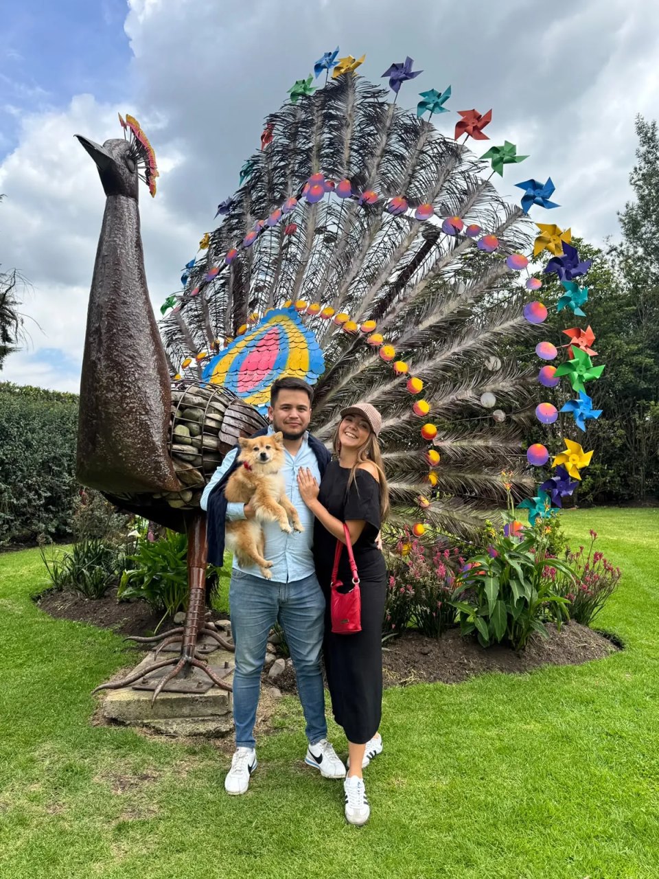 Danny y Luisa con su perro frente a un pavo real gigante de metal