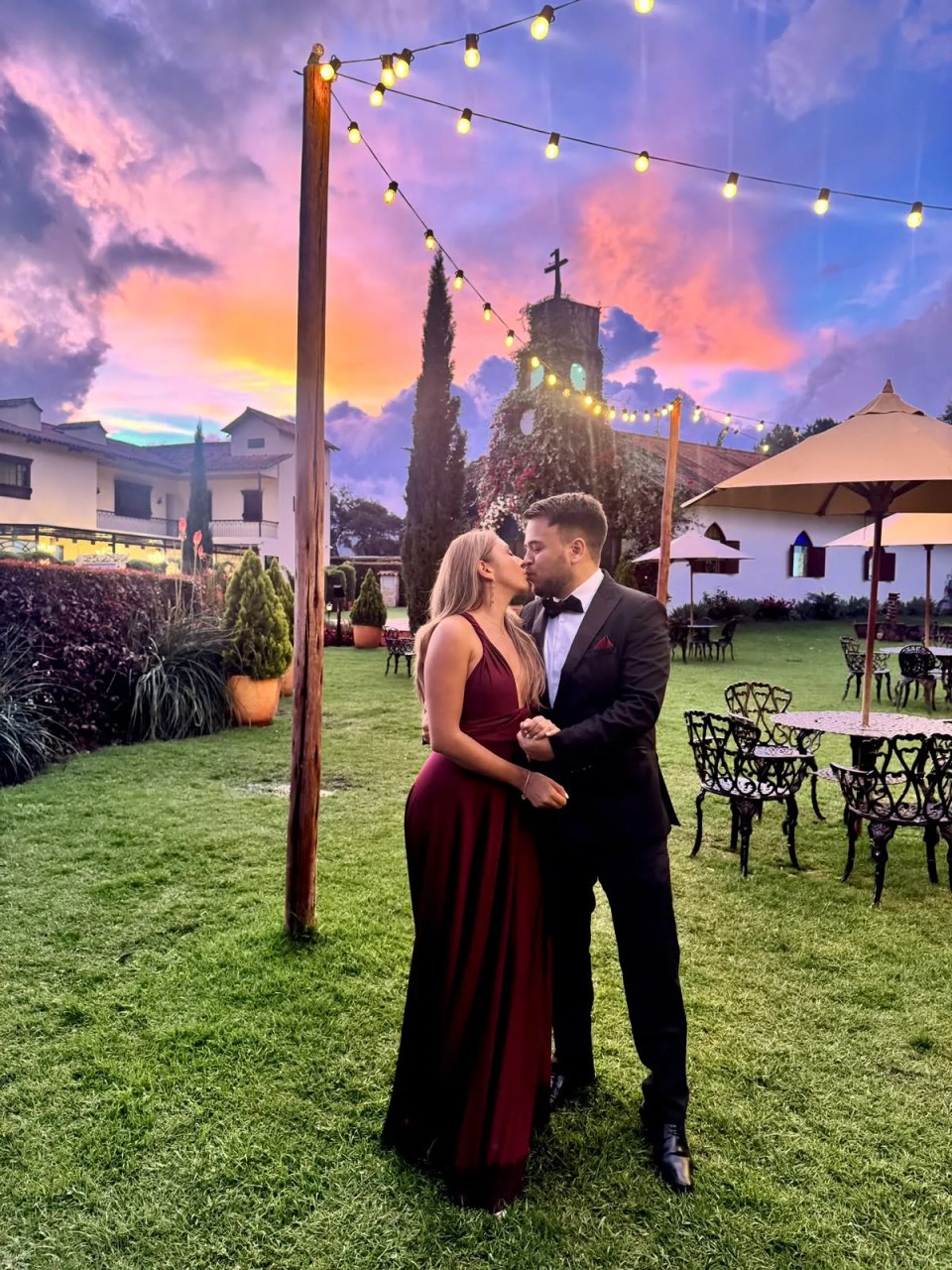 Danny y Luisa besándose al atardecer frente a una capilla